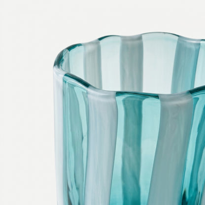 A macro close-up shot highlighting the undulating, wavy rim and thick, hand-blown texture of an Alessandro Coppola for Vetreria Arte di Murano aqua and white vertical candy-striped glass tumbler on a bright white background.