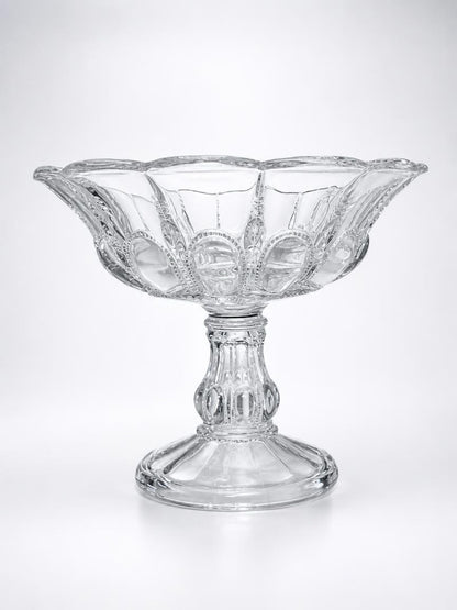 Studio profile shot of a vintage Early American Pattern Glass (EAPG) clear pedestal compote bowl in the "Beautiful Lady" pattern by Bryce Higbee, featuring a detailed multi-sided pedestal base and flared rim.
