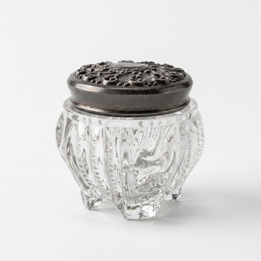 Side view of antique Victorian clear pressed glass vanity jar showing rare molded peg feet and intricate vertical zipper panels.