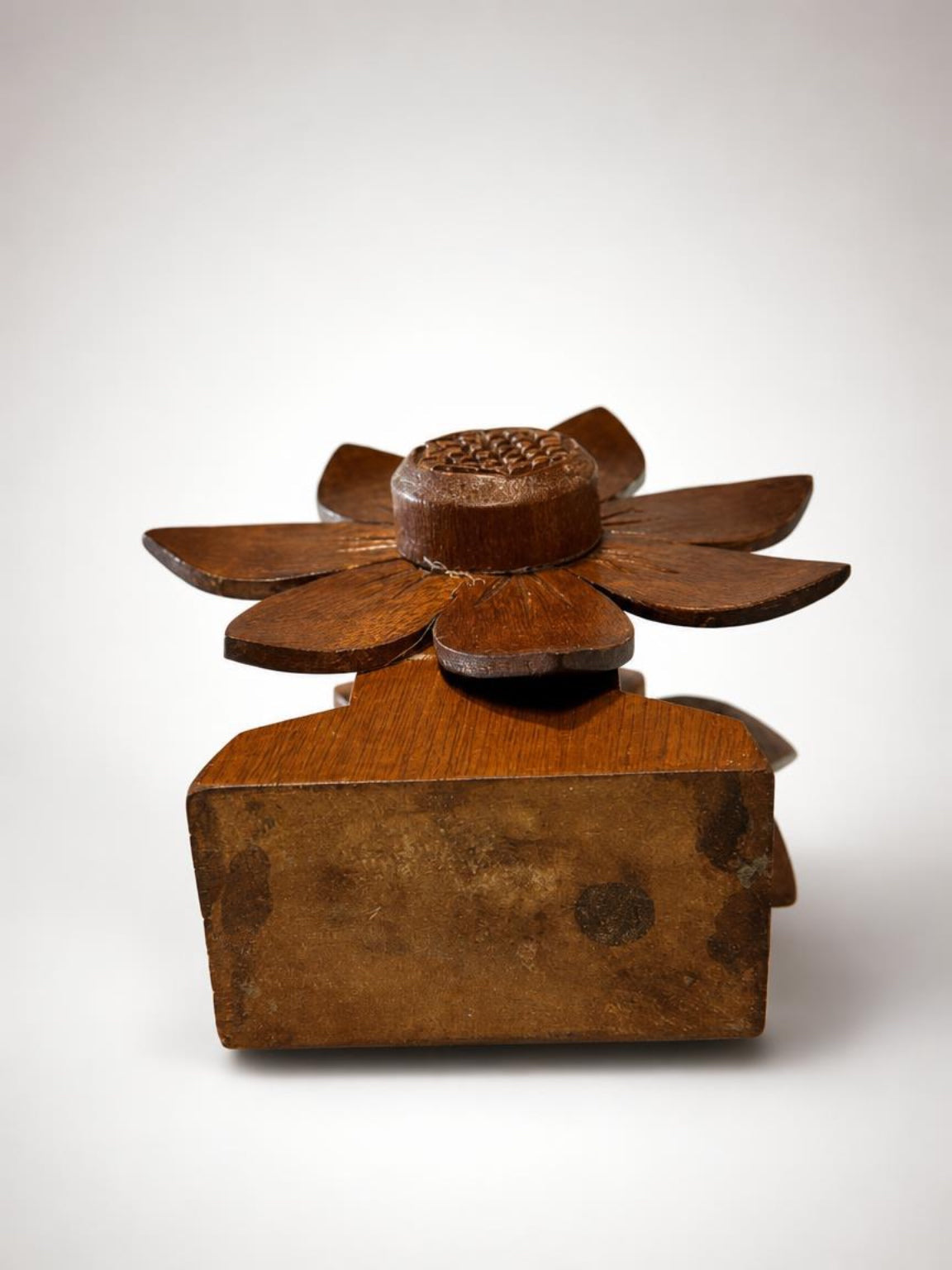Top-down angled view showing the underside of a vintage wooden napkin holder base, highlighting the authentic aged wood patina and the top of the hand-carved retro flower petals.