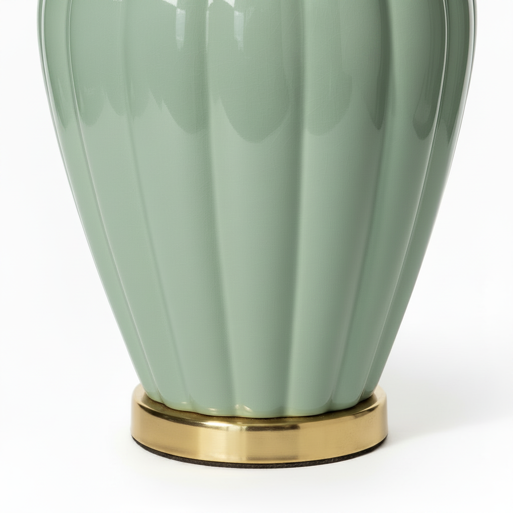 Close-up detail of vintage celadon ceramic table lamp base showing lobed melon urn silhouette tapering to circular polished brass plinth ring, high-gloss sage green glaze with light patina on brass base, white background