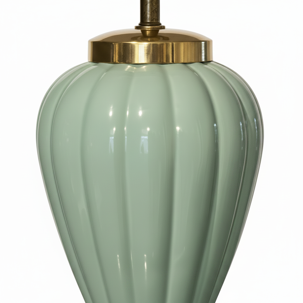 Close-up detail of high-gloss celadon mint ceramic lamp body showing deep vertical ribbed lobes and polished brass shoulder collar with light aged patina, soft reflective glaze catching directional light, white background