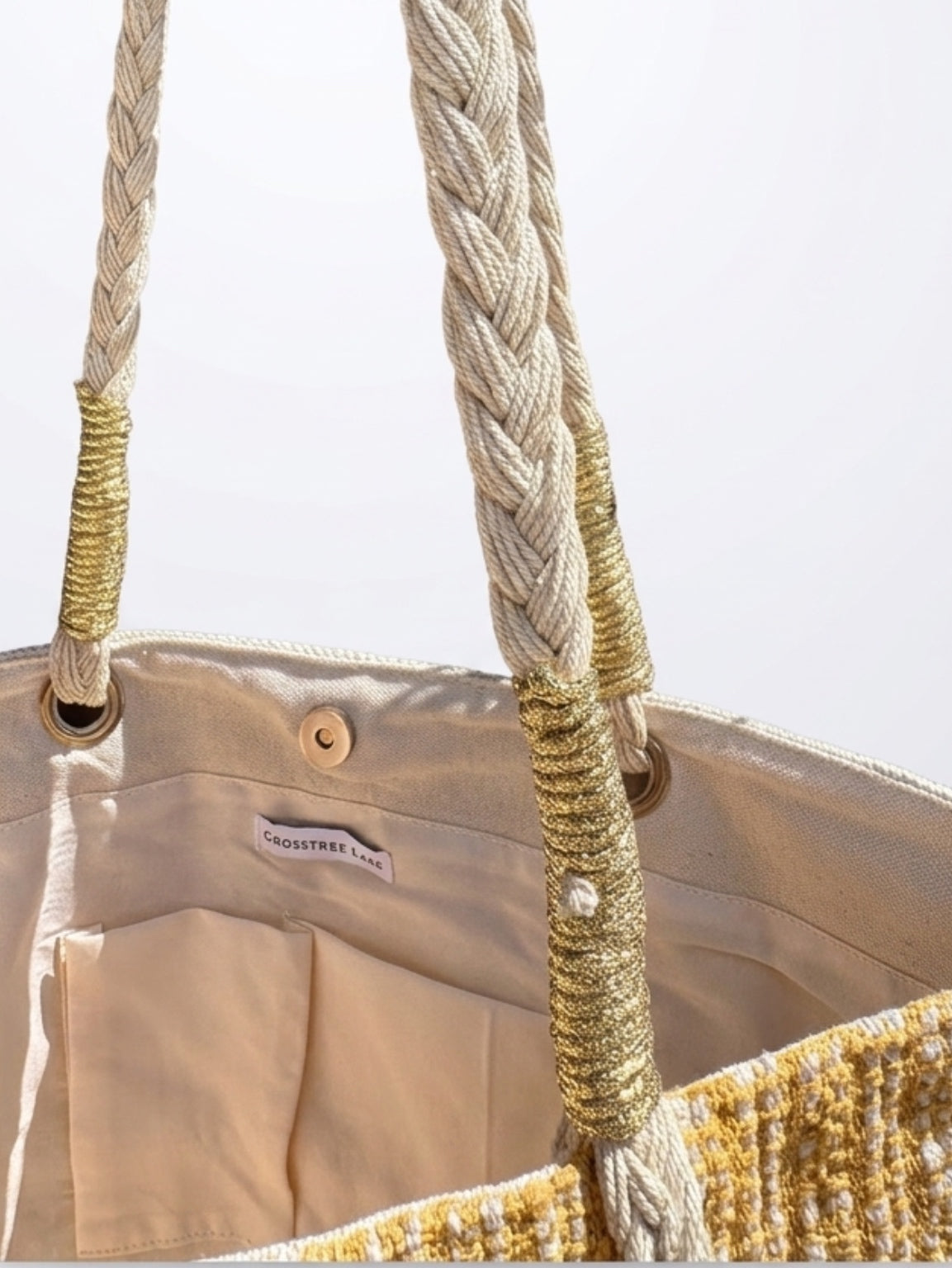 Close-up of the interior canvas lining on the Crosstree Lane tote bag, showcasing dual slip pockets, a metallic gold handle wrap, a magnetic snap closure, and the brand label.