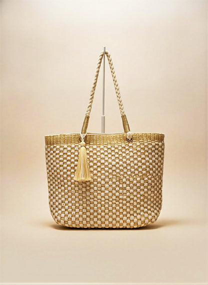 Studio portrait of the Crosstree Lane woven checkerboard tote bag with a matching oversized tassel, displayed elegantly against a neutral cream background.