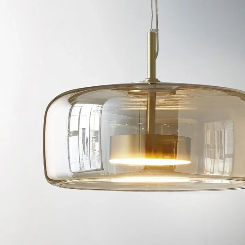 Modern pendant light with gold finish and clear glass shade on a white background