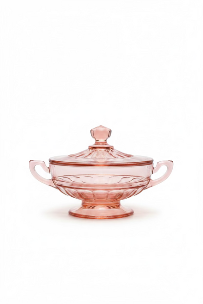 A full side view of the elegant pink depression glass lidded sugar bowl with handles and a pedestal base, highlighting its Art Deco design, set against a clean white background.