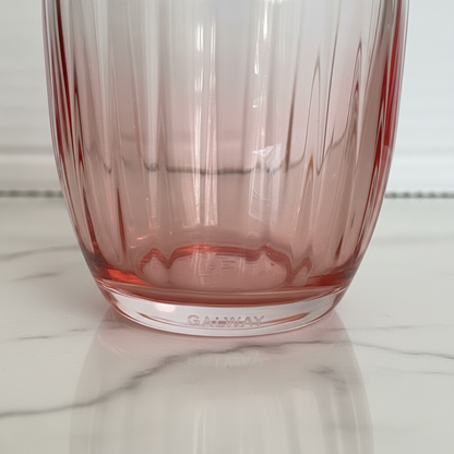 A close-up of a pink-tinted glass tumbler with vertical fluting, resting on a white marble surface. The brand name 'Galway' is embossed on the base.
