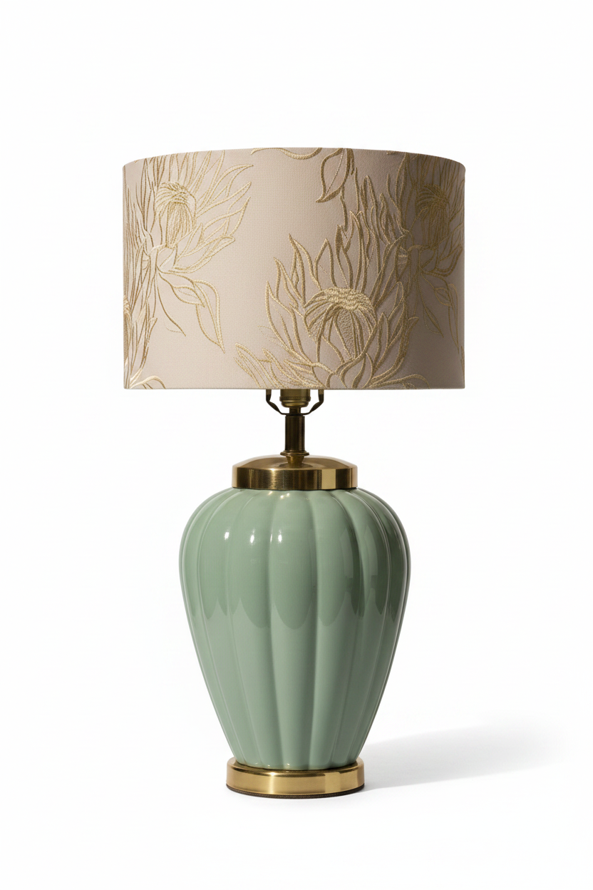 Vintage 1980s celadon glazed ceramic table lamp base in lobed melon urn form with polished brass shoulder collar and brass plinth, shown with embroidered cream botanical drum shade for scale on white background — shade not included