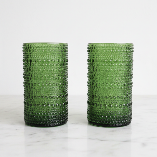 Pair of olive green hobnail highball glasses on white marble showing raised bead texture and cylindrical form, Home Essentials Halo