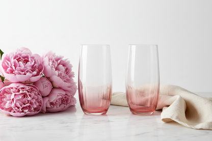 Pair of blush rose ombre highball glasses on white marble with pink peonies and linen napkin in soft natural light