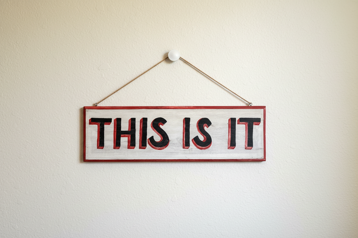 Hand-painted wooden sign reading THIS IS IT hanging on a neutral wall with natural jute rope, featuring red 3D shadow typography on a distressed white background.