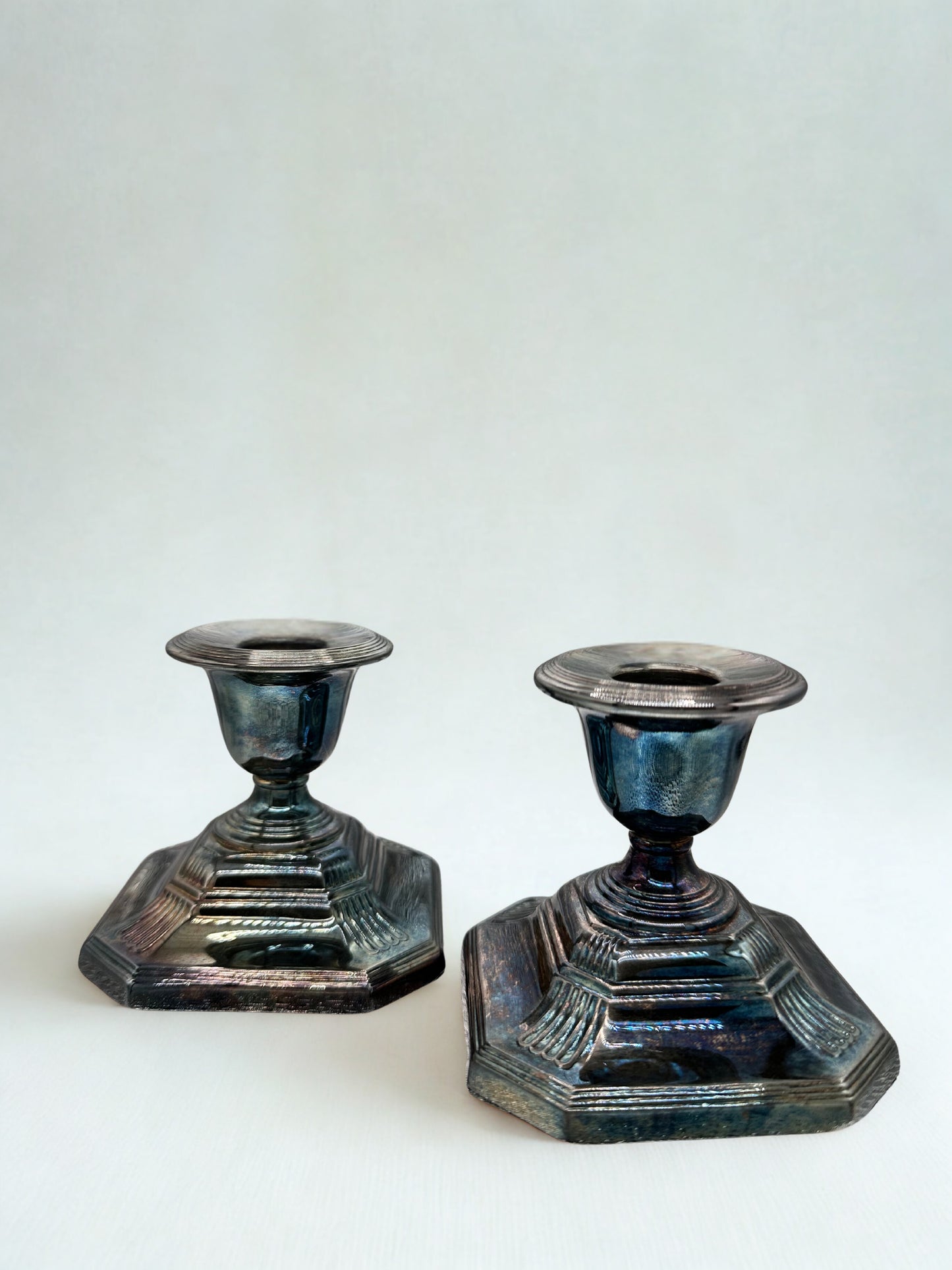 Two metallic candle holders on a white background