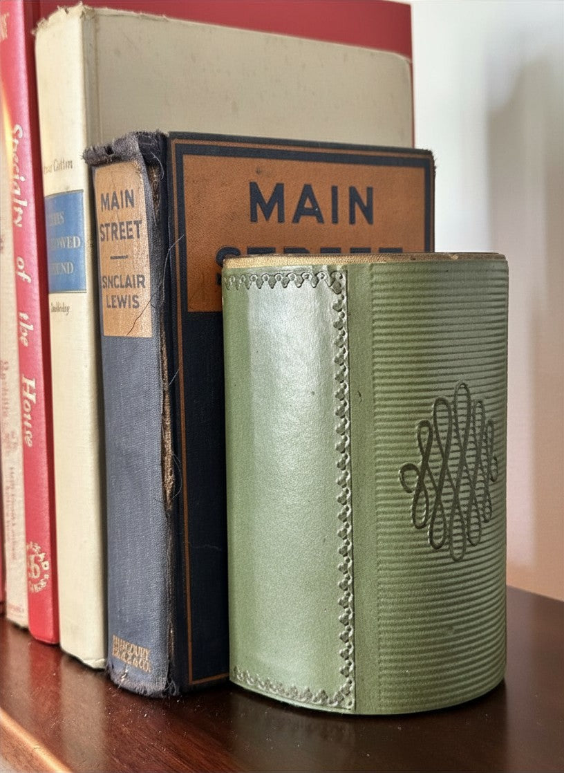 Detailed macro shot of a weighted sage green library bookend displaying the textured difference between the smooth, hand-tooled look front flap and the tightly ribbed curved side panel.