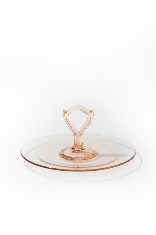 Translucent pink Depression glass tidbit server with a round ten inch tray and center loop handle set against a clean white backdrop.