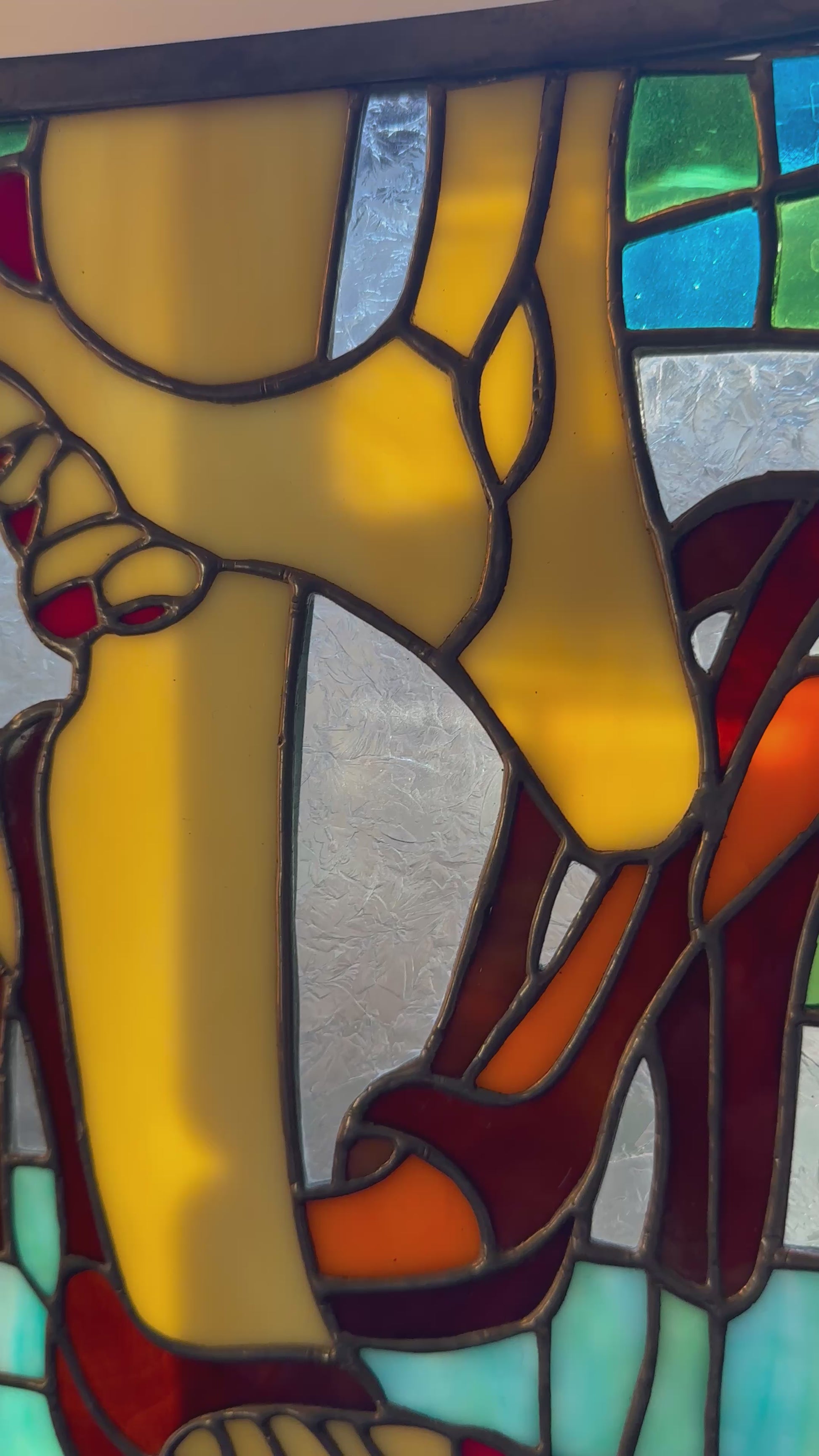 Colorful stained glass art featuring high-heeled shoes in red and orange shades, accented with yellow and green.