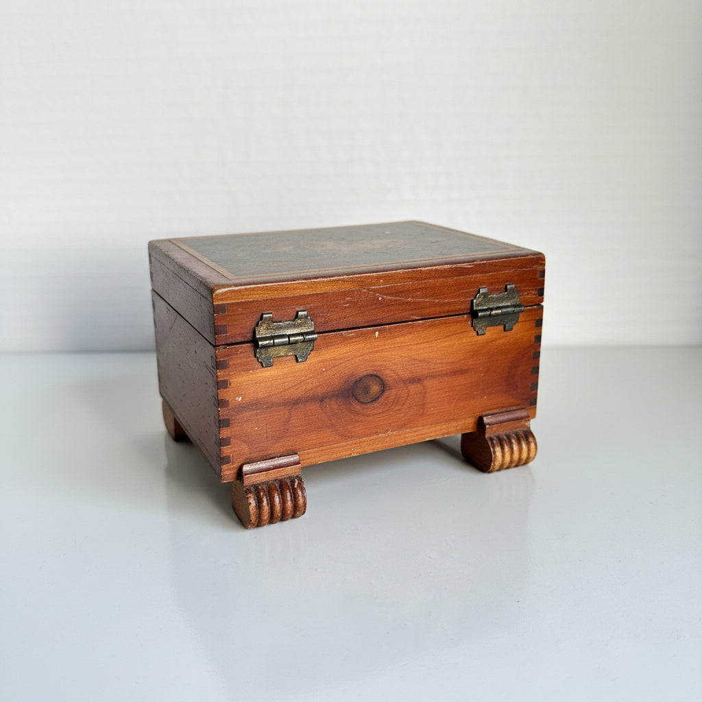 Three-quarter rear view of vintage cedar souvenir box showing original brass hinges, finger-joint corner construction, and carved fluted block feet at all four corners
