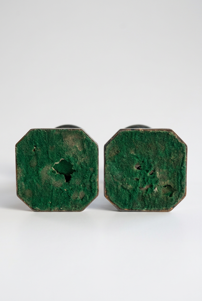 Undersides of two octagonal candlestick bases with green felt coverings showing worn patches, frayed areas, and small holes.