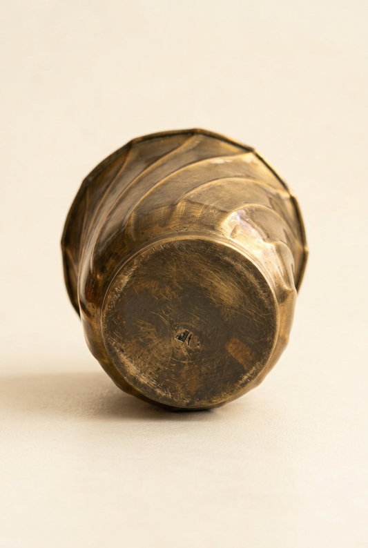  Underside of the vintage brass planter showing its round raised base, surface scratches, and darkened patina.