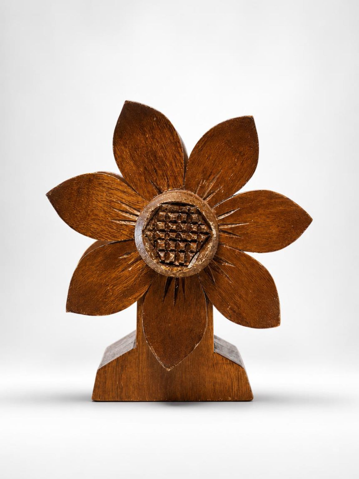 Front view of a 1970s vintage hand-carved wooden flower napkin holder with a stylized eight-petal design, a geometric cross-hatched center, and a flared pedestal base on a crisp white background.