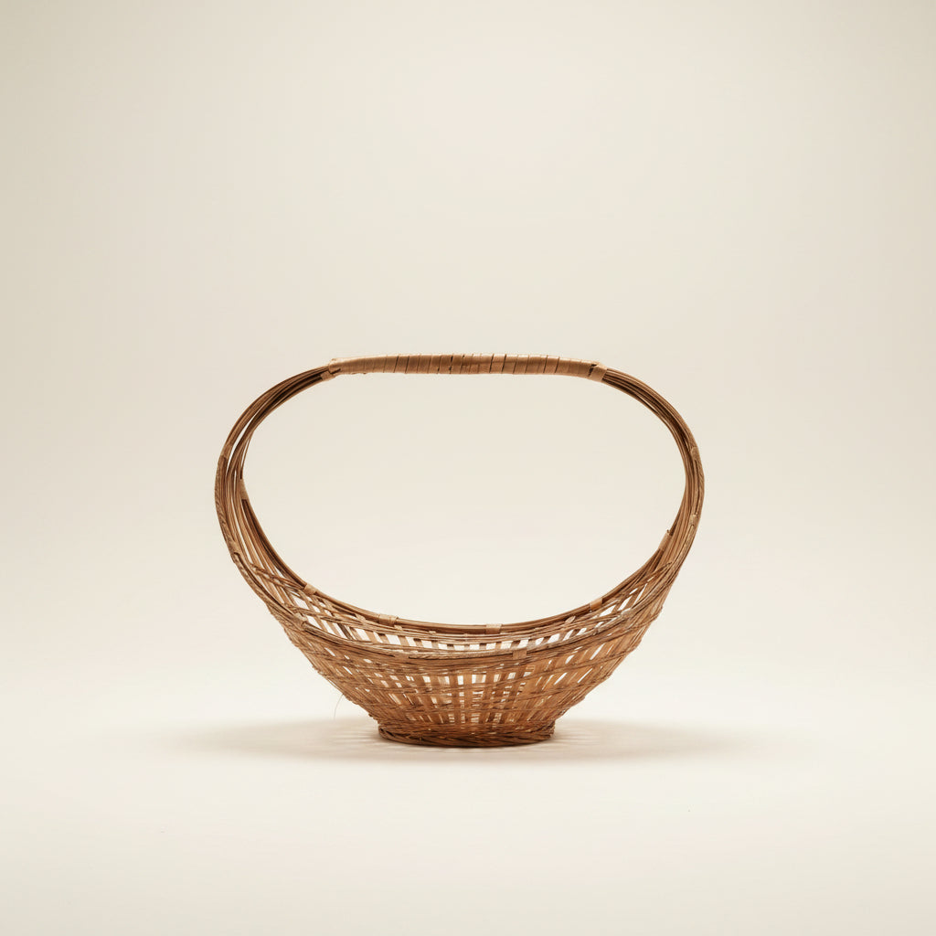 A vintage mid-century modern split-bamboo basket featuring a dramatic, large elliptical hoop handle and an open-weave, boat-shaped base against a neutral background