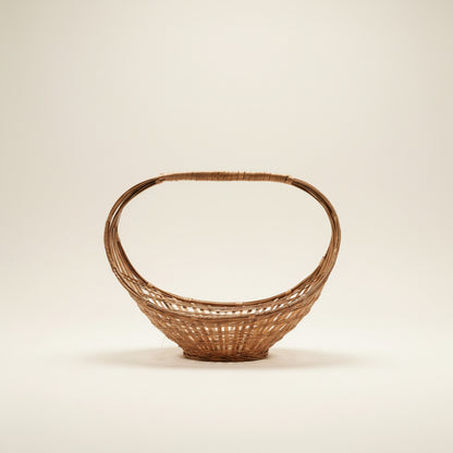 A vintage mid-century modern split-bamboo basket featuring a dramatic, large elliptical hoop handle and an open-weave, boat-shaped base against a neutral background