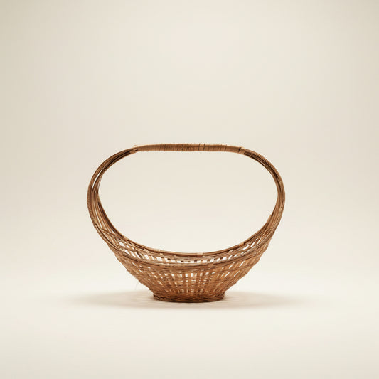 A vintage mid-century modern split-bamboo basket featuring a dramatic, large elliptical hoop handle and an open-weave, boat-shaped base against a neutral background