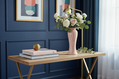 vintage pink ceramic vase with a ribbon motif sitting on a modern console in a dark blue room