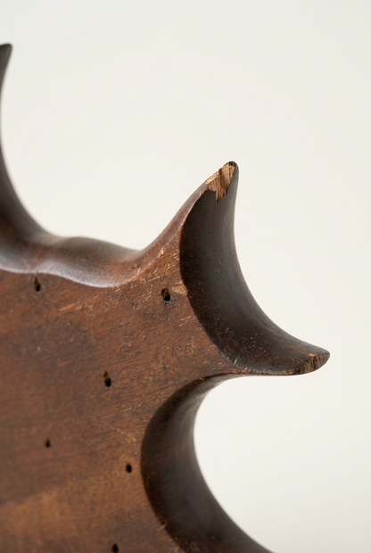 Close-up of the wooden angelfish holder showing a chipped fin tip, exposed wood, and scratches in the brown finish.