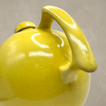Yellow ceramic jug handle close-up against a warm greige background